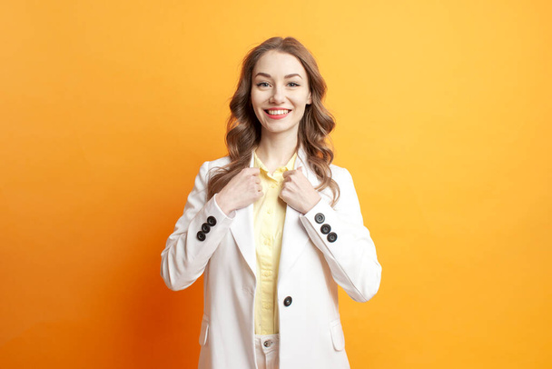 femme d'affaires réussie en costume blanc et blazer sur un fond isolé orange, gestionnaire de filles en vêtements d'affaires - Photo, image