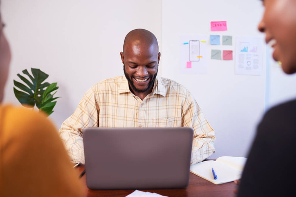 Czarny deweloper pracuje na laptopie podczas spotkania z kolegami. Wysokiej jakości zdjęcie - Zdjęcie, obraz