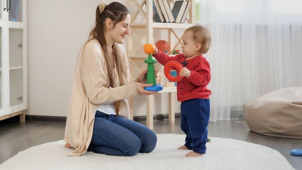 Little baby boy with mother assembling toy tower and playing with toys. - Foto, Imagen