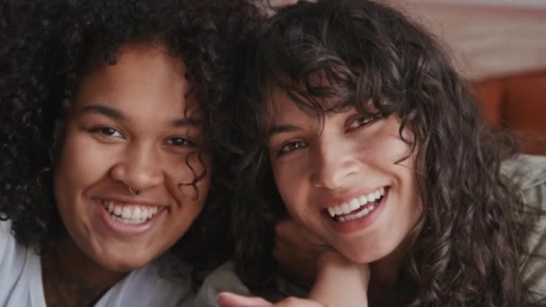 Lähikuva muotokuva viehättävä etnisesti monipuolinen lesbo pari tai parhaita ystäviä hymyilee kameralle - Materiaali, video