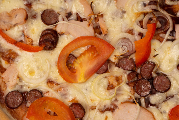Νόστιμη πίτσα με σαλάμι, λουκάνικα, τυρί, κρεμμύδια και σάλτσα. - Φωτογραφία, εικόνα