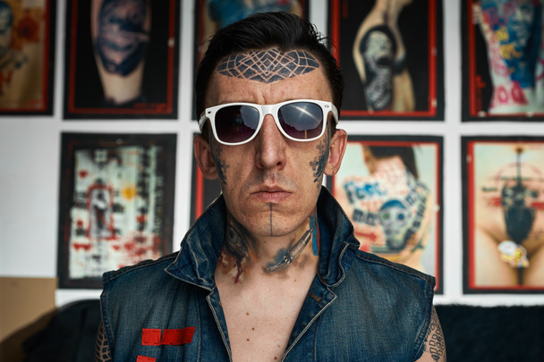 Tattoo artist in denim vest and sunglasses - 写真・画像