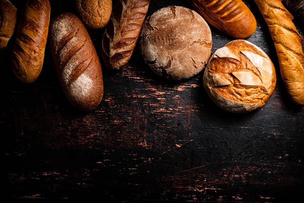 A variety of delicious bread on the table. Against a dark background. High quality photo - Фото, изображение