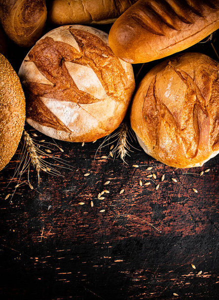 Different types of bread with spikelets. Against a dark background. High quality photo - Zdjęcie, obraz