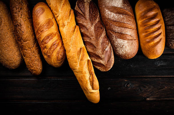 Different types of fresh crispy bread. On a wooden background. High quality photo - Φωτογραφία, εικόνα