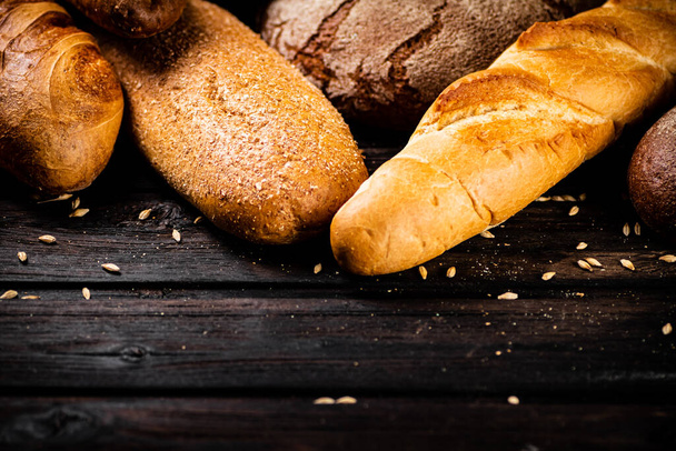 Different types of fresh crispy bread. On a wooden background. High quality photo - Valokuva, kuva