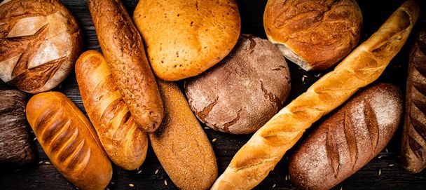 Different types of fresh crispy bread. On a wooden background. High quality photo - Foto, Imagen