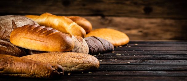 Different types of freshly baked bread. On a wooden background. High quality photo - Fotoğraf, Görsel