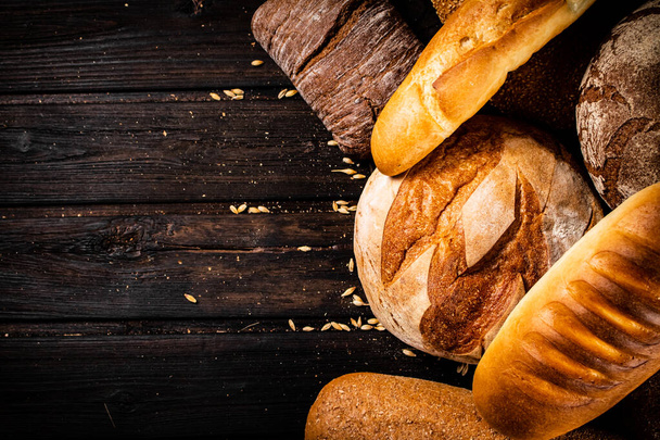 Different types of freshly baked bread. On a wooden background. High quality photo - Valokuva, kuva