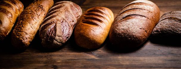 Different types of freshly baked bread. On a wooden background. High quality photo - Foto, Imagem