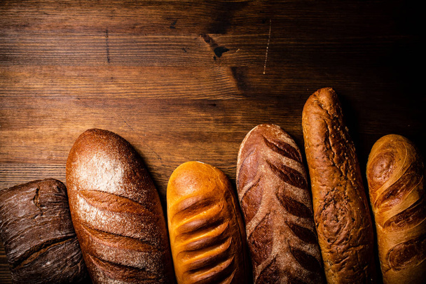 Different types of freshly baked bread. On a wooden background. High quality photo - Foto, afbeelding
