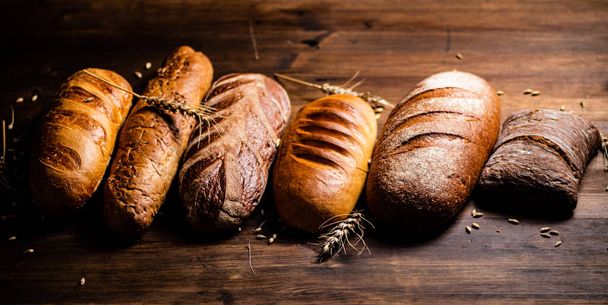 Diferentes tipos de pão delicioso. Em um fundo de madeira. Foto de alta qualidade - Foto, Imagem
