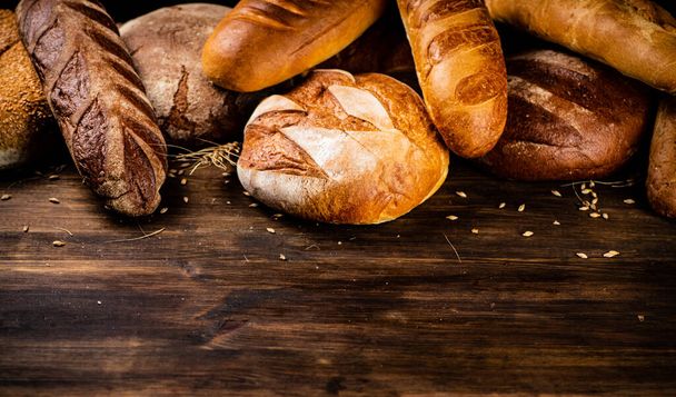 Different kinds of delicious bread. On a wooden background. High quality photo - Foto, imagen