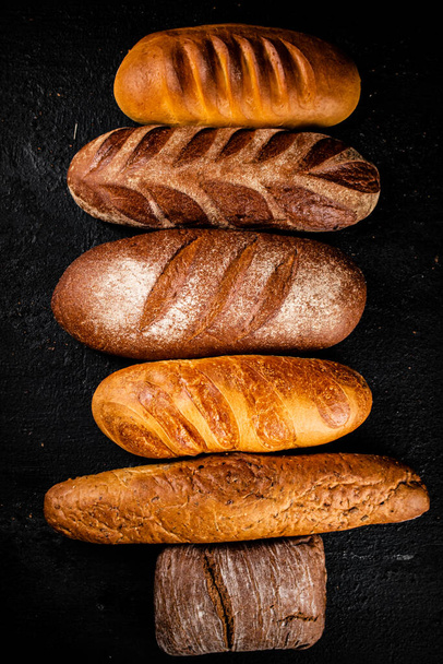 Разнообразный ароматный свежий хлеб. На черном фоне. Высокое качество фото - Фото, изображение