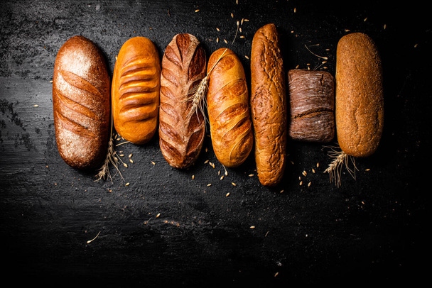 A variety of fragrant fresh bread. On a black background. High quality photo - Fotoğraf, Görsel
