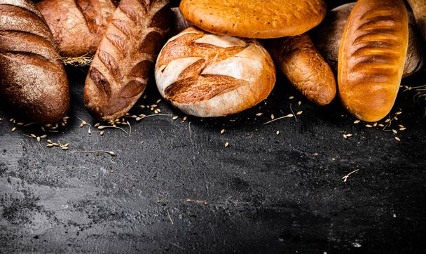 Different types of fresh bread on the table. On a black background. High quality photo - Zdjęcie, obraz