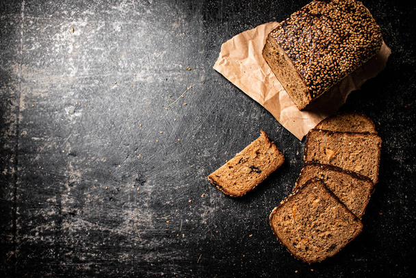Sliced rye bread on paper. On a black background. High quality photo - Foto, afbeelding