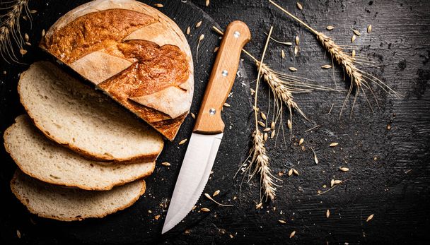 Sliced on a stone board wheat bread with grains. On a black background. High quality photo - Fotoğraf, Görsel