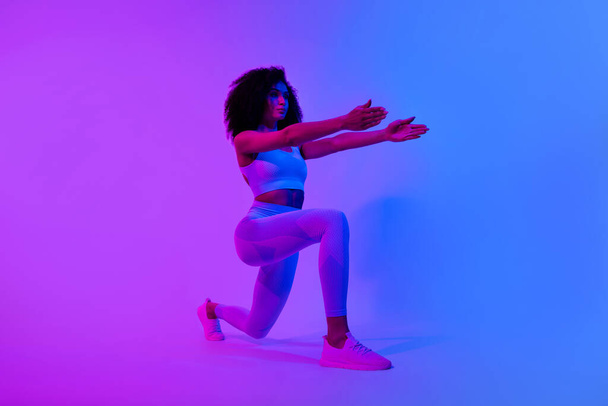 Full size profile photo of concentrated fitness coach girl doing lunges isolated on ultraviolet color neon background. - Foto, Imagem