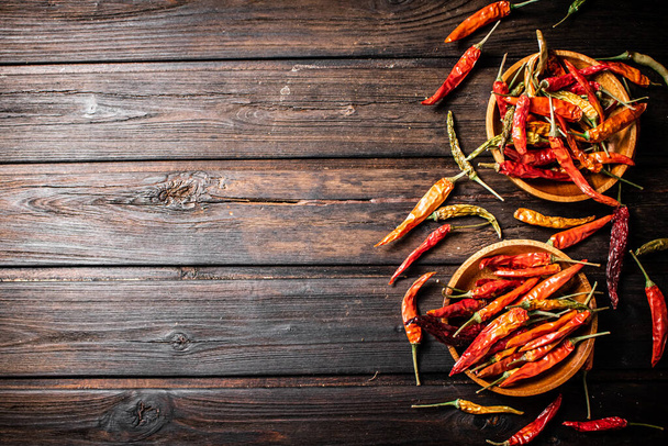 Pods of dried chili peppers in a plate. On a wooden background. High quality photo - Fotó, kép