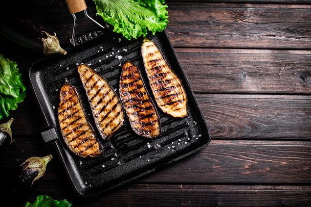 Pieces of eggplant grilled in a grill pan. On a wooden background. High quality photo - Foto, immagini
