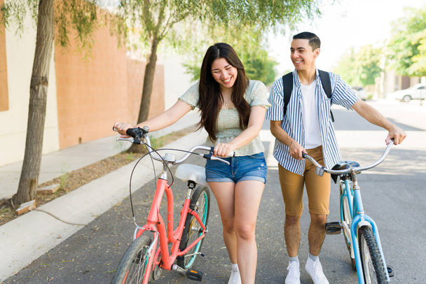Очень счастливая пара смеется и веселится во время прогулки на свежем воздухе на своих винтажных велосипедах летом - Фото, изображение