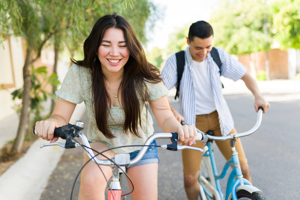 陽気美しい女性と白人男性は夏の屋外でヴィンテージバイクに乗っている間に一緒に笑って楽しんでいます - 写真・画像