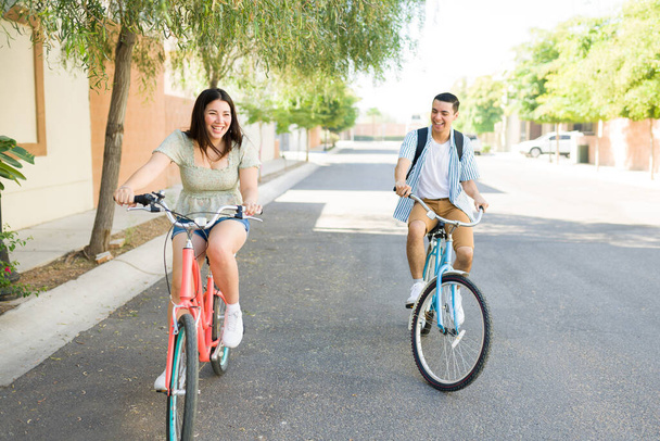 Щаслива дівчина і хлопець сміються і розважаються під час їзди на своїх старовинних велосипедах на відкритому повітрі під час красивої літньої дати
 - Фото, зображення