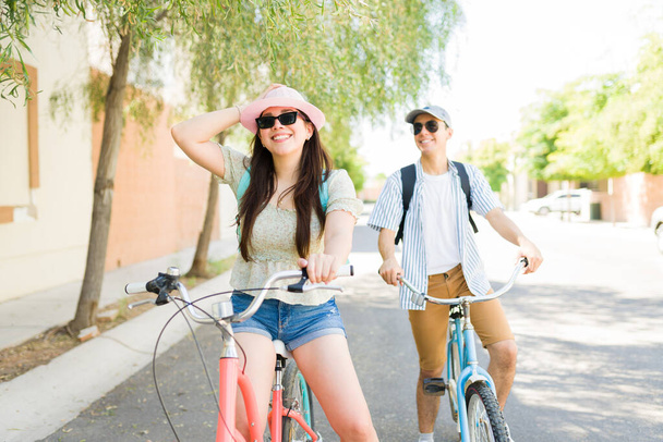 Красивая белая женщина смеется, радуясь, катаясь на винтажных велосипедах со своим парнем на открытом воздухе и идя на свидание - Фото, изображение