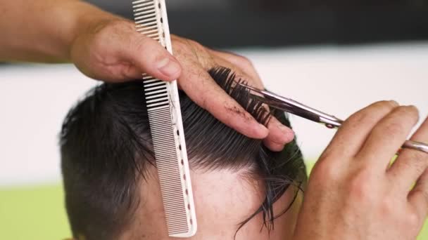 Friseur schneidet einem jungen Mann mit Schere und Kamm die Haare. Hochwertiges 4k Filmmaterial - Filmmaterial, Video