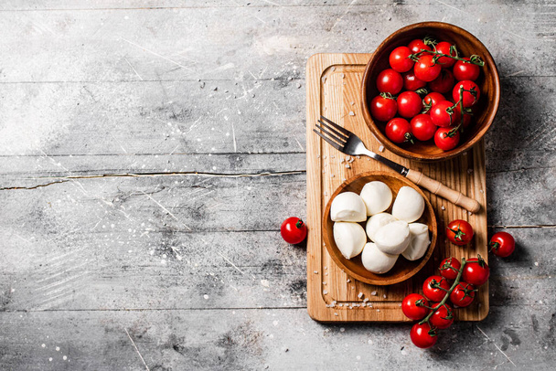 Mozzarella cheese on a wooden cutting board with cherry tomatoes. On a gray background. High quality photo - Fotó, kép