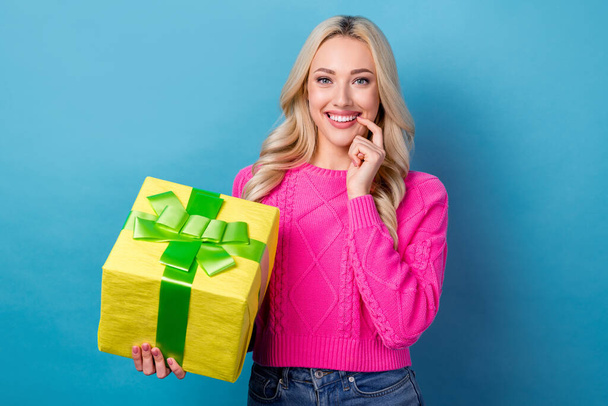 Portrait of positive gorgeous woman with wavy hairdo wear pink pullover hold big present box finger lips isolated on blue color background. - Foto, immagini