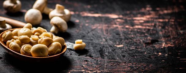 Pickled mushrooms in a wooden plate on the table. Against a dark background. High quality photo - 写真・画像