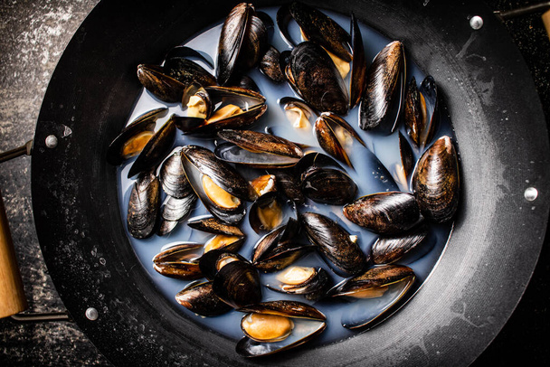 Pot of mussels on the table. On a black background. Top view. High quality photo - Фото, изображение