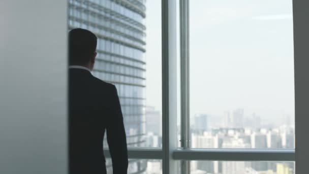 asiatico business uomo a piedi fino a il finestra guardando il città in ufficio - Filmati, video