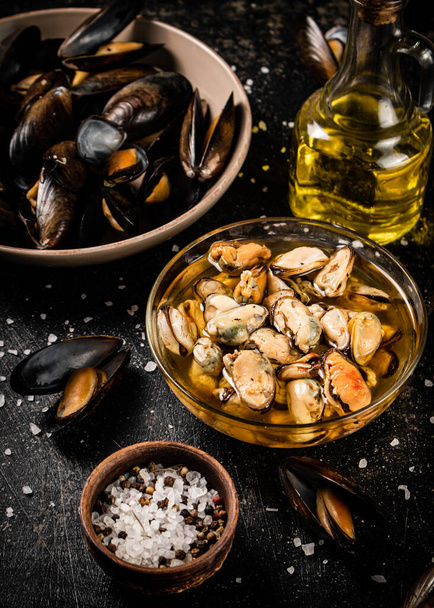 Pickled mussels in a glass bowl with spices. On a black background. High quality photo - Фото, зображення
