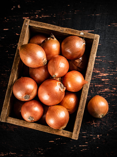 Onions in a wooden box. Against a dark background. High quality photo - 写真・画像