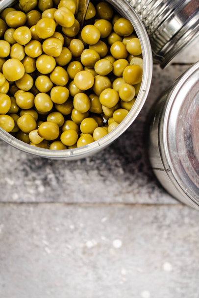 Canned green peas in a tin can on the table. On a gray background. High quality photo - Fotó, kép