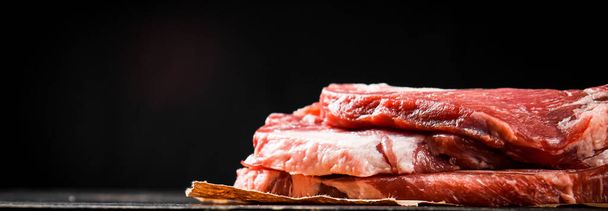 A pile of raw pork steak on the table. On a black background. High quality photo - Foto, afbeelding