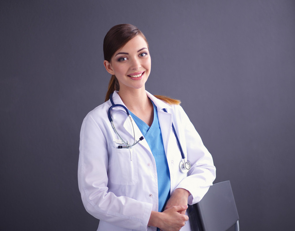 Krásná žena lékař stojící v blízkosti stolice izolované šedé pozadí - Fotografie, Obrázek