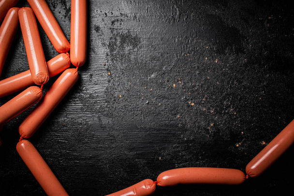 Delicious sausages boiled on the table. On a black background. High quality photo - Foto, afbeelding