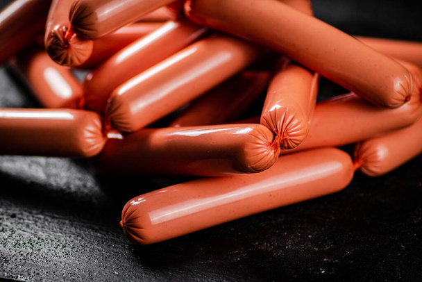 Delicious sausages boiled on the table. On a black background. High quality photo - Fotoğraf, Görsel