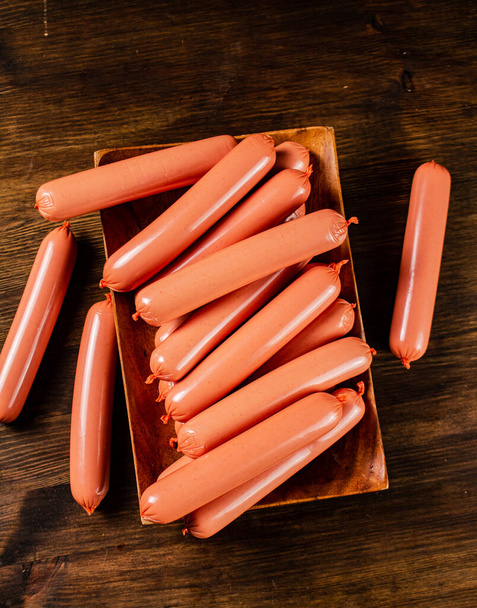 A wooden plate full of sausages. On a wooden background. High quality photo - Foto, afbeelding