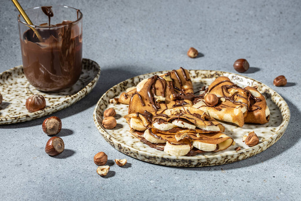 Homemade thin crepes with chocolate spread and hazelnuts for breakfast or dessert. banner, menu, recipe place for text, top view. - Φωτογραφία, εικόνα