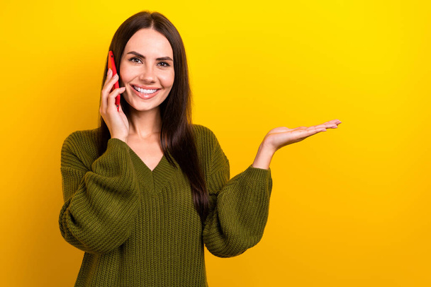 Photo of cheerful nice person speak telephone arm palm hold empty space isolated on yellow color background. - Foto, Imagem