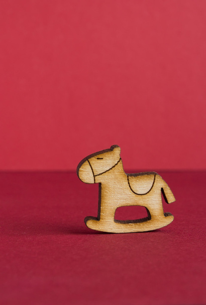 Wooden icon of children's rocking horse on red background - Фото, зображення