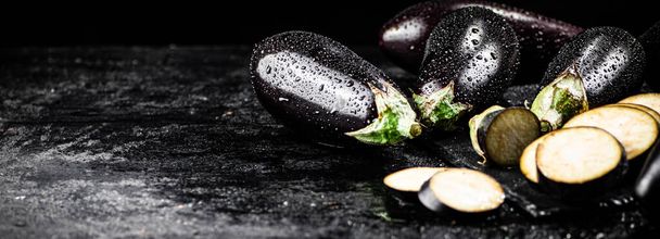 Pieces of ripe eggplant on a stone board. On a black background. High quality photo - Φωτογραφία, εικόνα