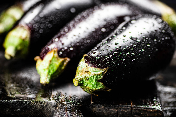 Ripe eggplant with droplets of water. On a black background. High quality photo - Photo, Image