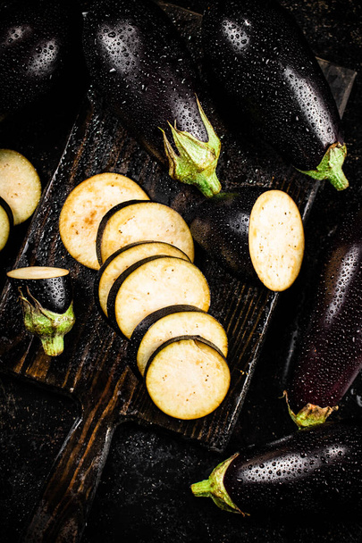 Cut into pieces on a cutting board of eggplant. On a black background. High quality photo - Foto, Imagen