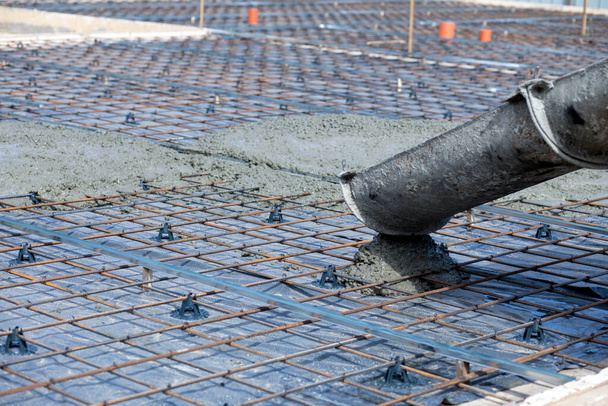 Betonový stroj slučuje beton do výztužného sítě.Beton se vylévá z vaničky na výztuž. - Fotografie, Obrázek